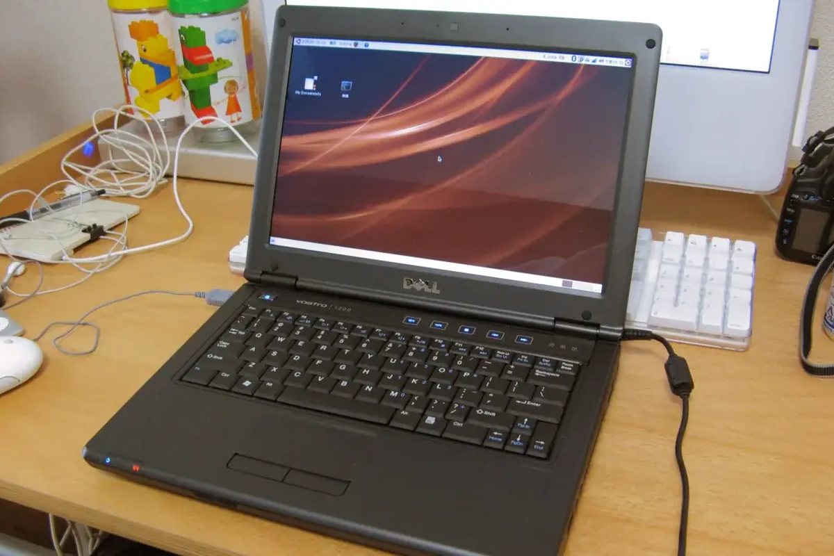 Otwarty laptop i kubek na stole przy oknie mieszkania — pomoc informatyczna w domu