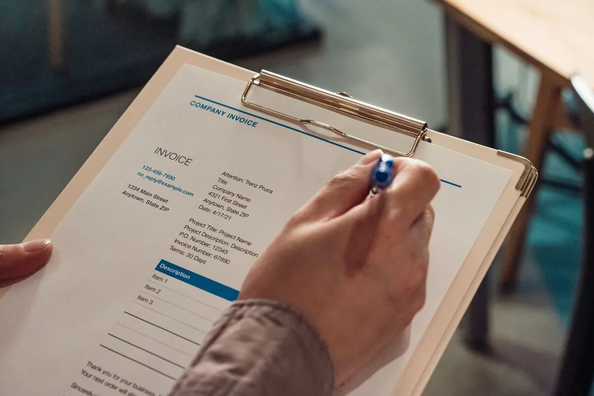 Dłoń wypełniająca fakturę na podkładce — obsługa systemu iFirma